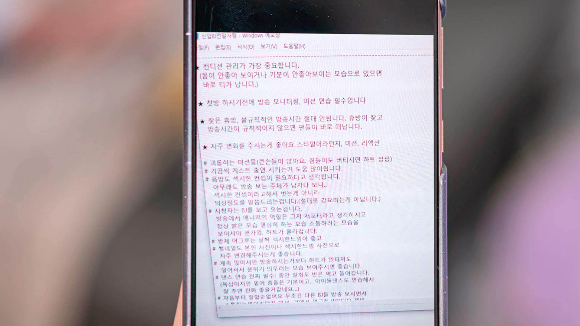휴대폰 화면에 '신입BJ전달사항.txt'이라는 제목의 글이 보인다.