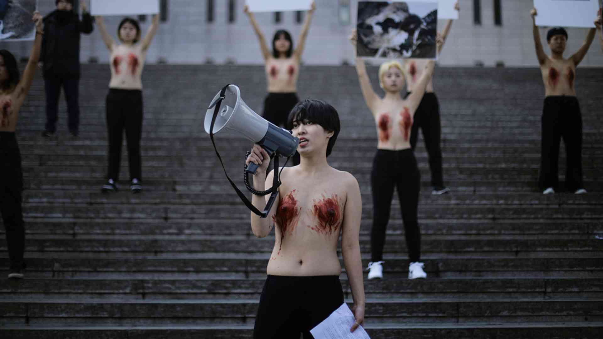 2020년 2월 14일 DxE가 진행한 시위 현장. 동물 강제 착유를 비판하며 서울 광화문 세종문화회관에 모였다. 시위 참여자들이 상의를 탈의하고, 유두를 붉은색으로 칠했다. 이 시위를 기획한 은영이 확성기를 들었다. 현장 사진 제공 DxE.