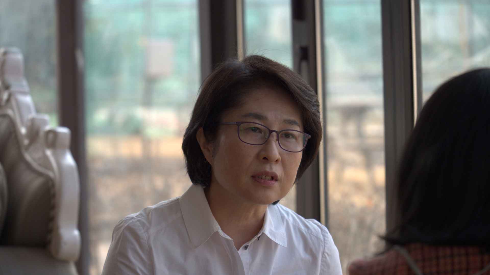 정은주씨가 인터뷰에 응하고 있다. 단발머리를 하고, 흰색 셔츠와 안경을 착용했다. 