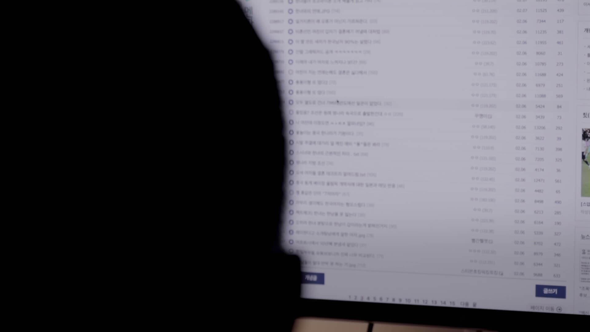 한 사람이 컴퓨터 모니터로 익명 인터넷 사이트 디씨인사이드의 글 목록을 보고 있다.