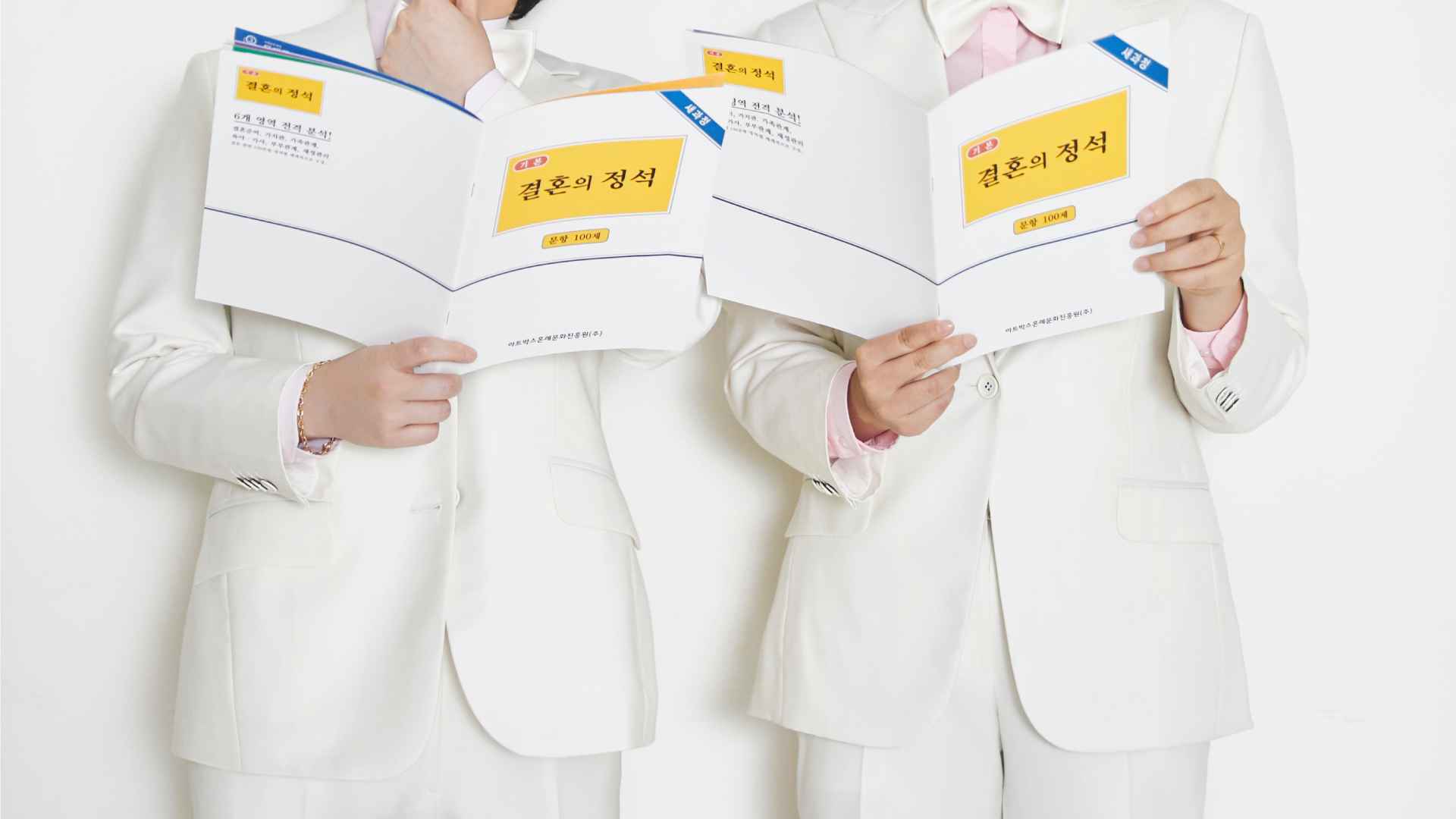 웨딩 화보 촬영을 한 지한과 수영 커플. 두 사람 모두 흰색 슈트를 입고, <결혼의 정석>이라고 쓰여 있는 책을 들고 있다.