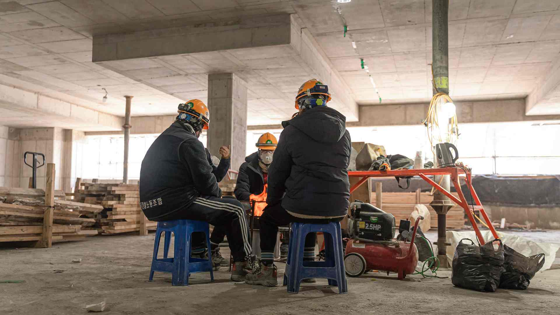 건설 현장에서 작업자들이 불을 쬐며 쉬고 있다.
