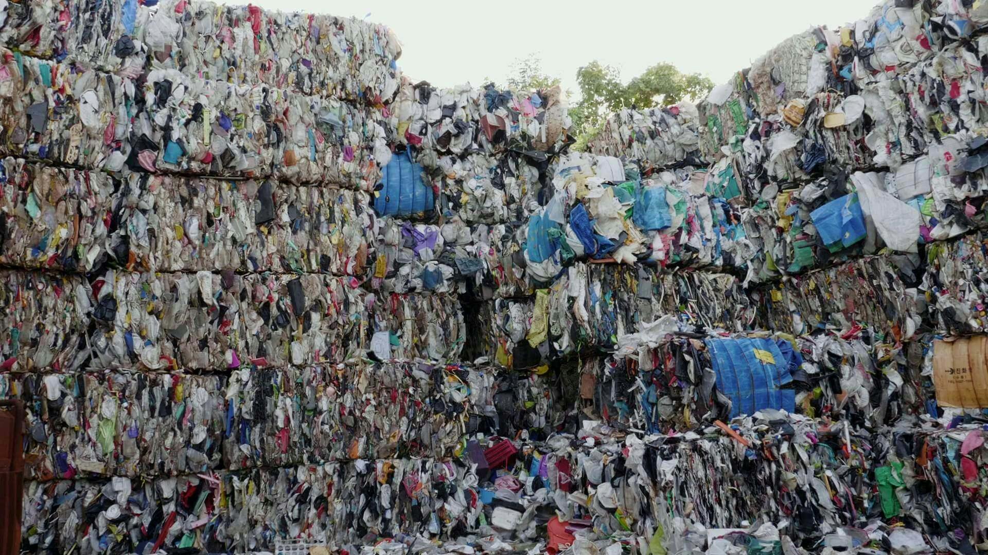 벽돌처럼 압축된 플라스틱 쓰레기가 약 5m 높이로 벽처럼 쌓여 있다.